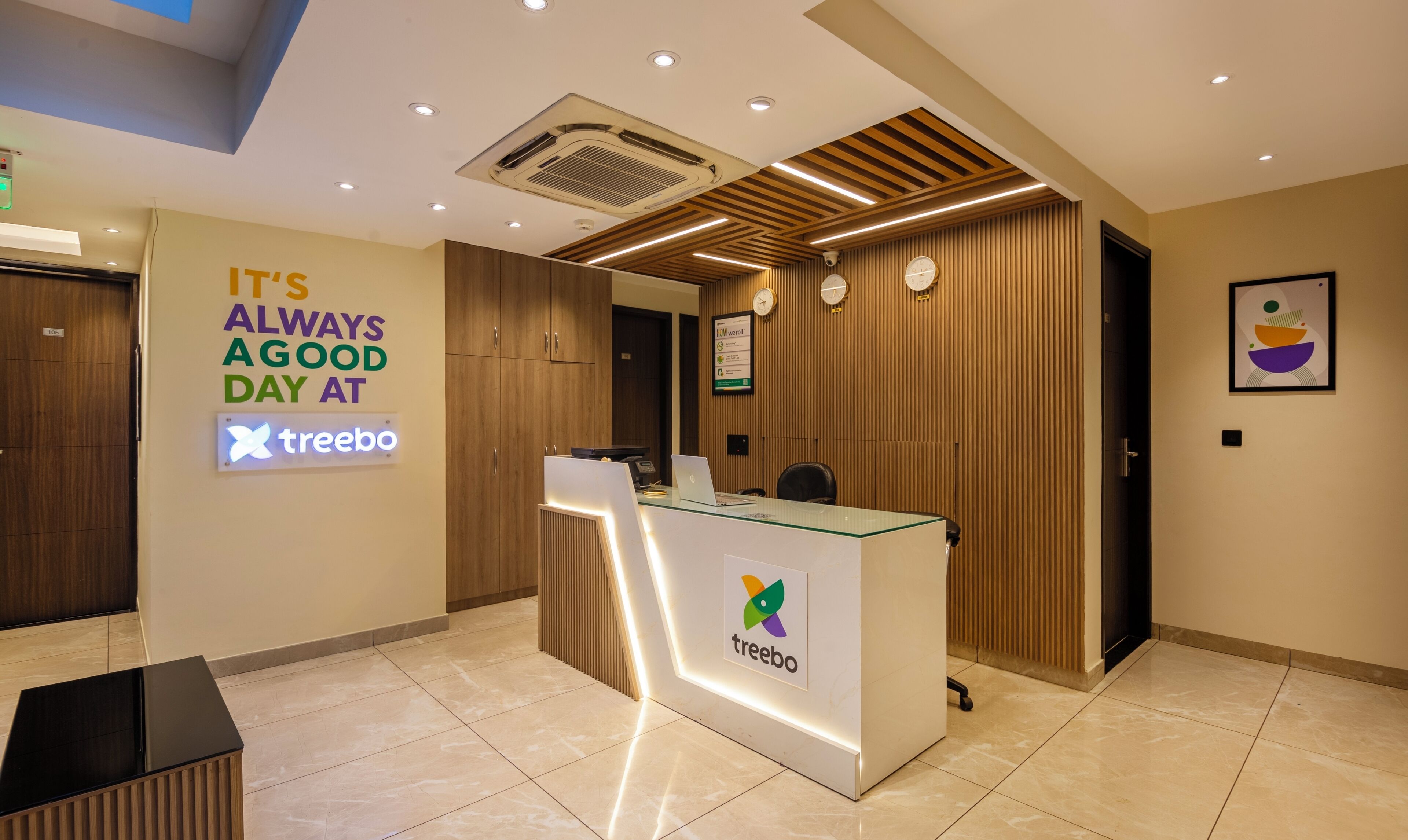A reception desk with a 'treebo' logo, a clock, and a sign saying "IT'S ALWAYS A GOOD DAY AT treebo".