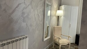 Une pièce avec un mur décoré d’un motif imitant le marbre, un radiateur, une chaise, un miroir, une lampe et une armoire.