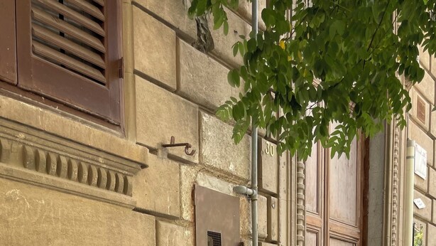 Un bâtiment en pierre avec une porte en métal, une fenêtre avec des volets et une grille en métal.
