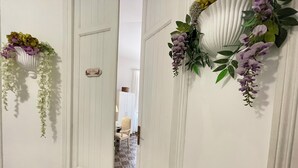 Un couloir avec des portes blanches, un sol à motifs et des décorations florales suspendues.