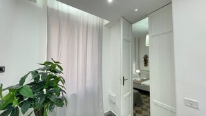 Une chambre d’hôtel avec un lit, une table de chevet, une lampe et une plante en pot.