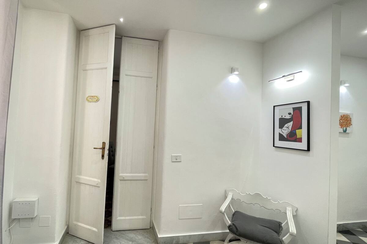 A hallway with a white door, a bench, and a framed picture on the wall.
