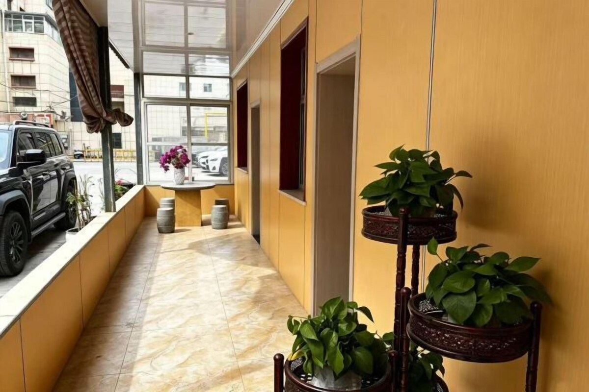 A corridor with potted plants, a window, and a door.
