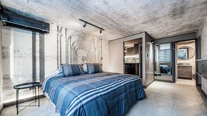 Une chambre à coucher avec un grand lit, une petite table de chevet et un dressing.