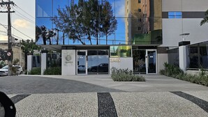 A modern building with a glass facade reflecting trees and a clear sky. - Aquarius Residence (Fortaleza)