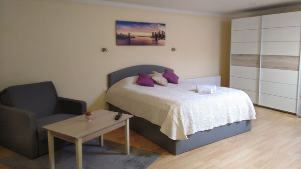 Ein Schlafzimmer mit Bett, Nachttisch, Stuhl, Tisch und einem Bild an der Wand.