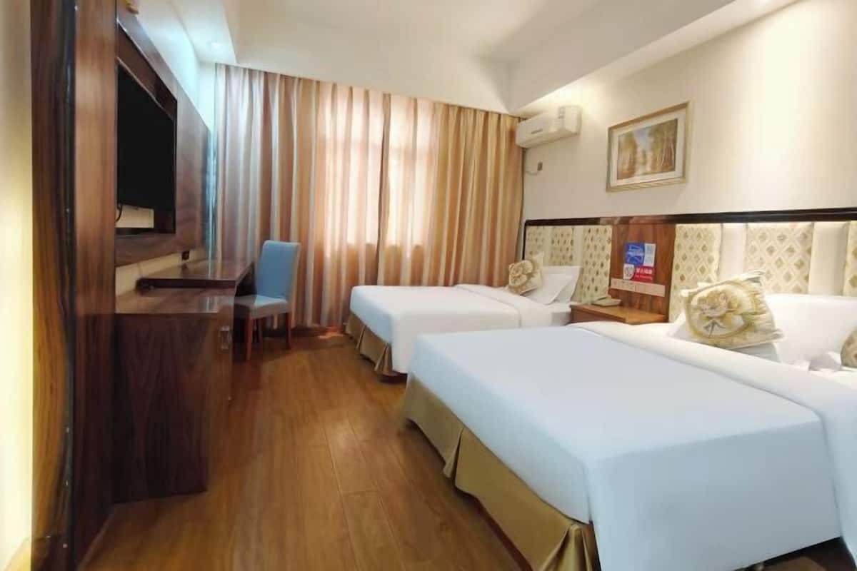 Una habitación de hotel con dos camas, un escritorio, una silla y un televisor.
