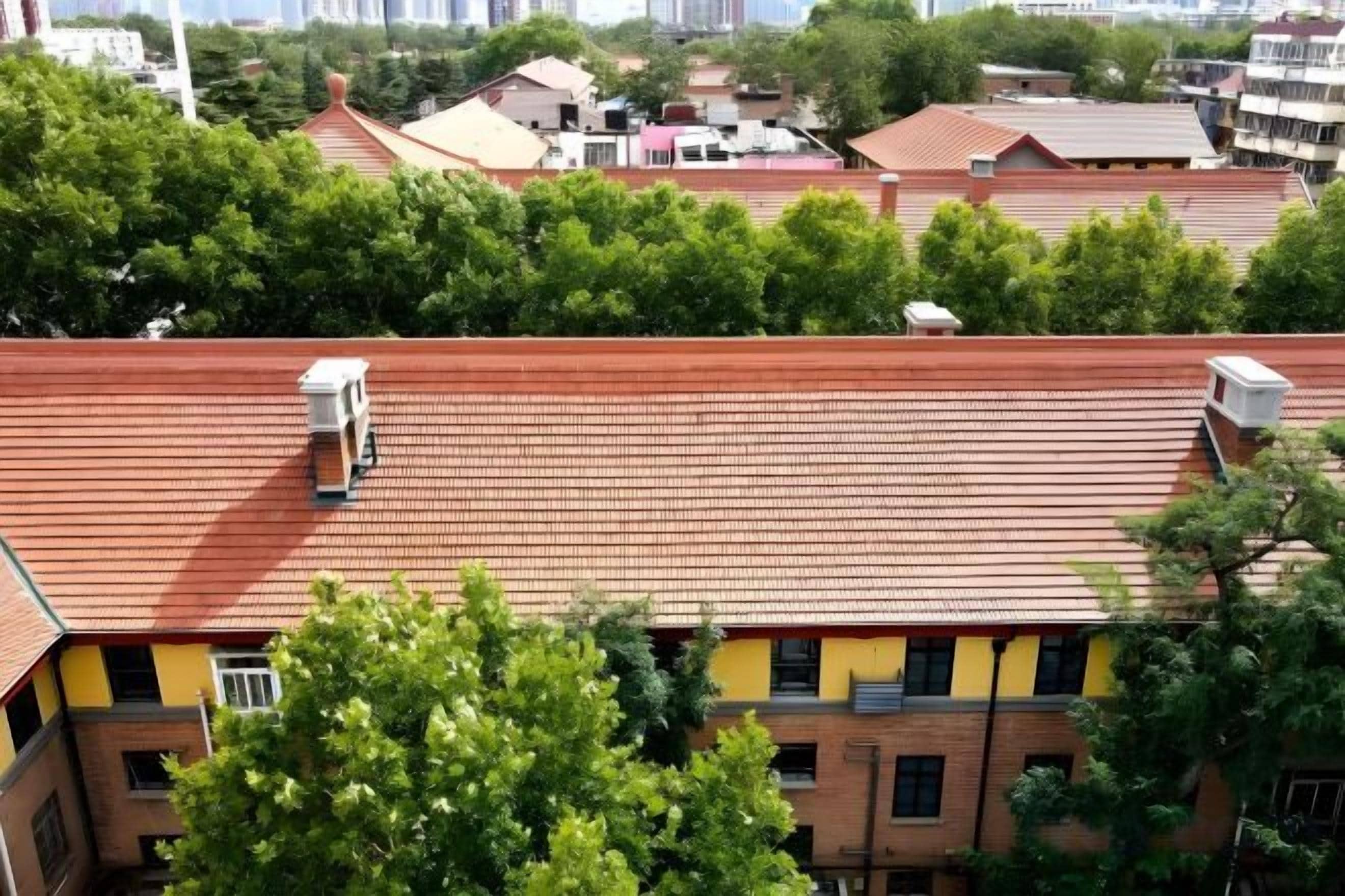 A building with a red-tiled roof, multiple windows, and a visible water tank on the roof.