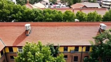 A building with a red-tiled roof, multiple windows, and a visible water tank on the roof.