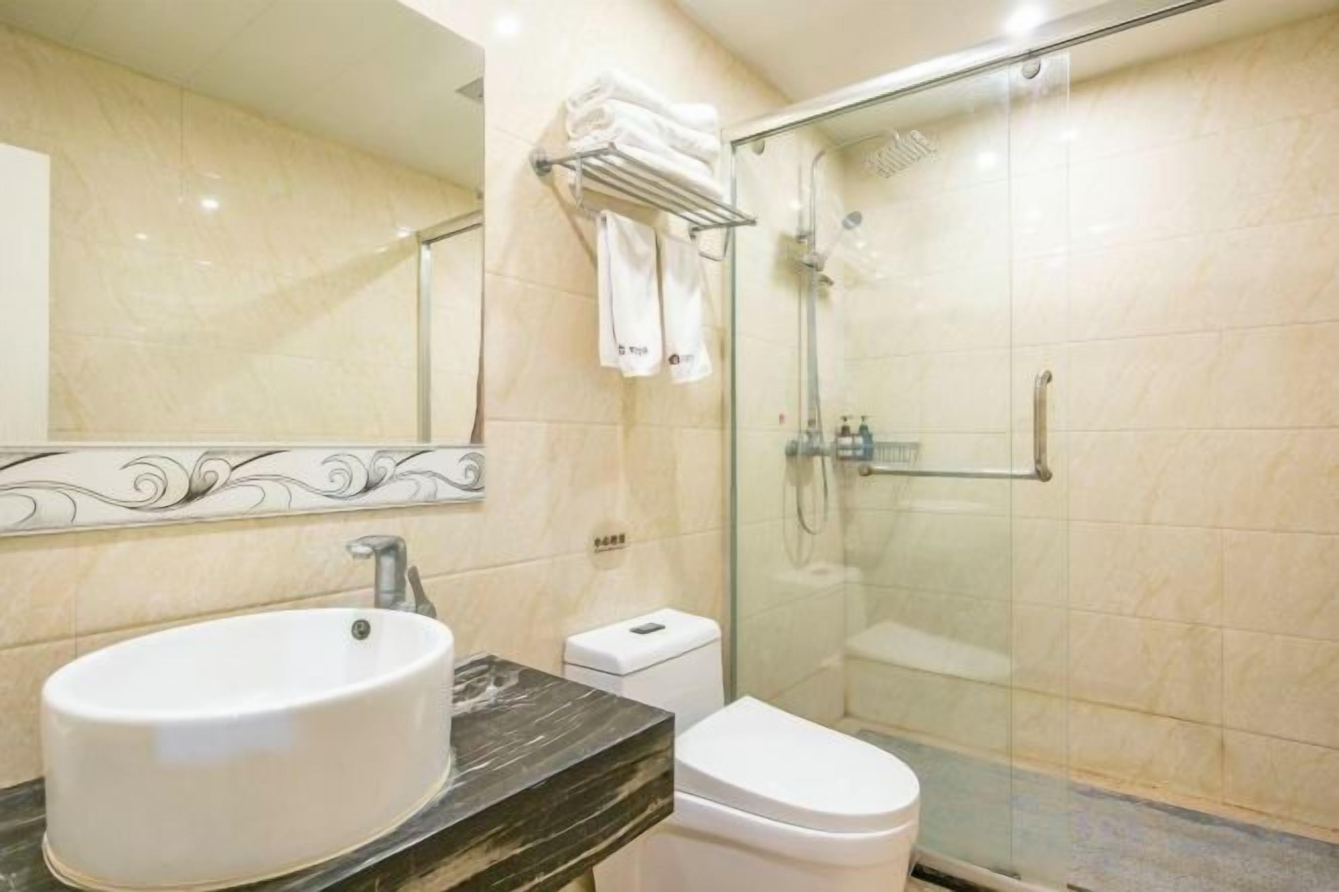 Une salle de bain avec un lavabo en marbre, des toilettes et une douche à parois de verre.