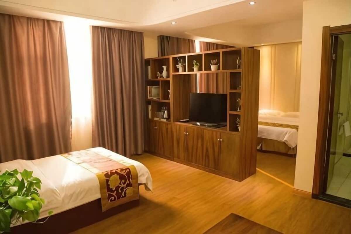 Una habitación de hotel con una cama, un televisor, una estantería y un escritorio.