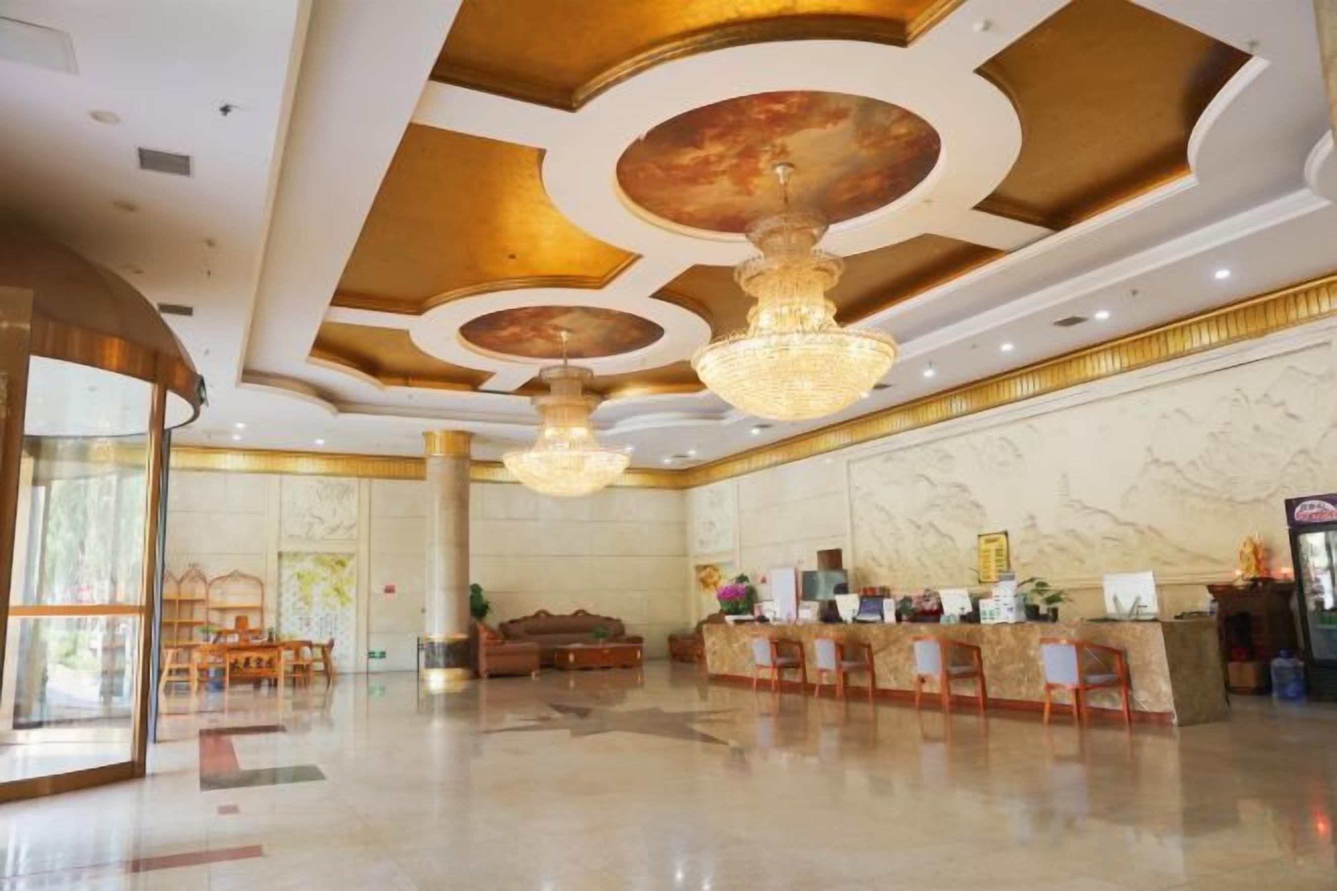 Un hall d’hôtel comprenant un comptoir d’accueil, un espace salon et un lustre.