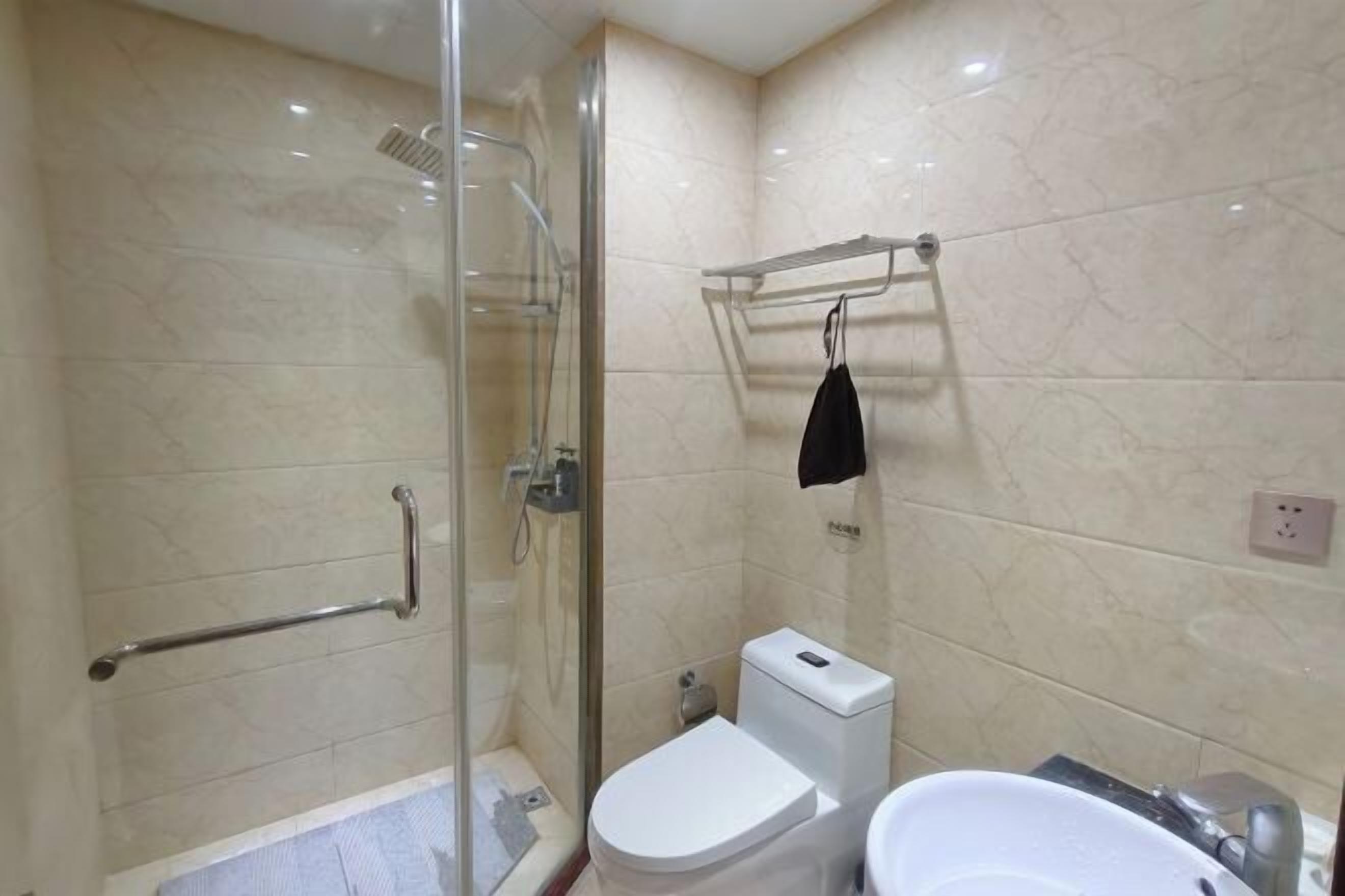 A bathroom with a glass-enclosed shower, a toilet, and a sink.