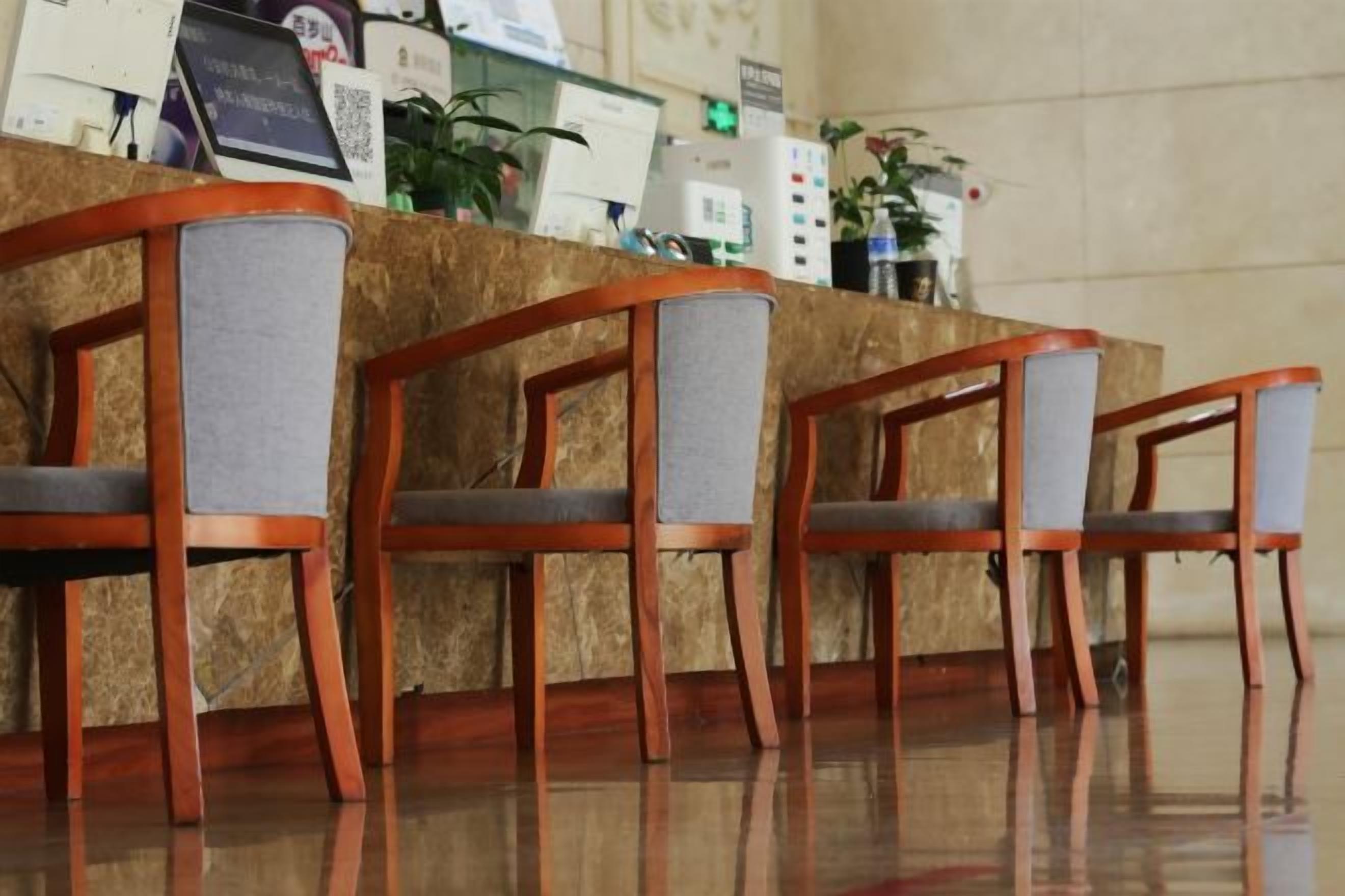 Una zona de recepción con mostrador de mármol, sillas de madera y una máquina de café.