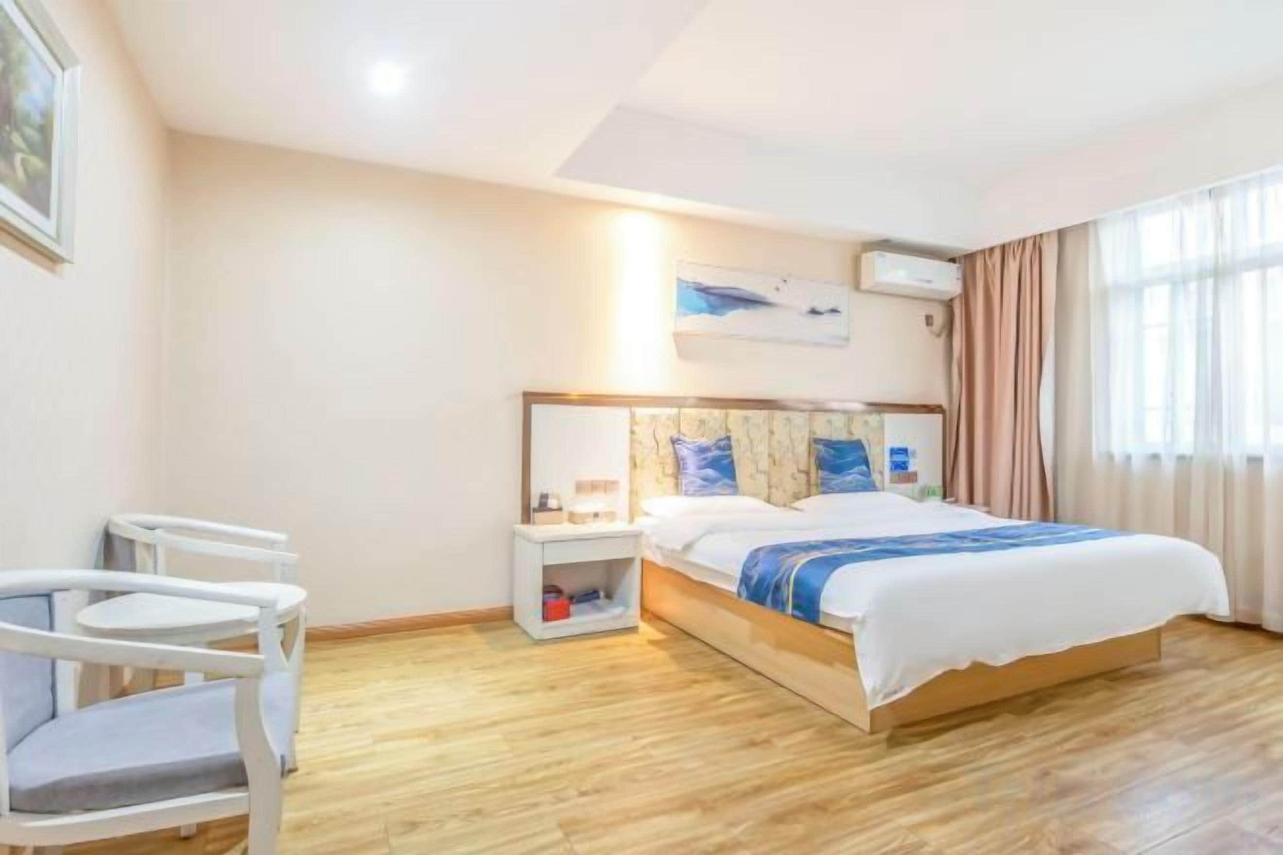 A hotel room with a bed, bedside table, and a chair.
