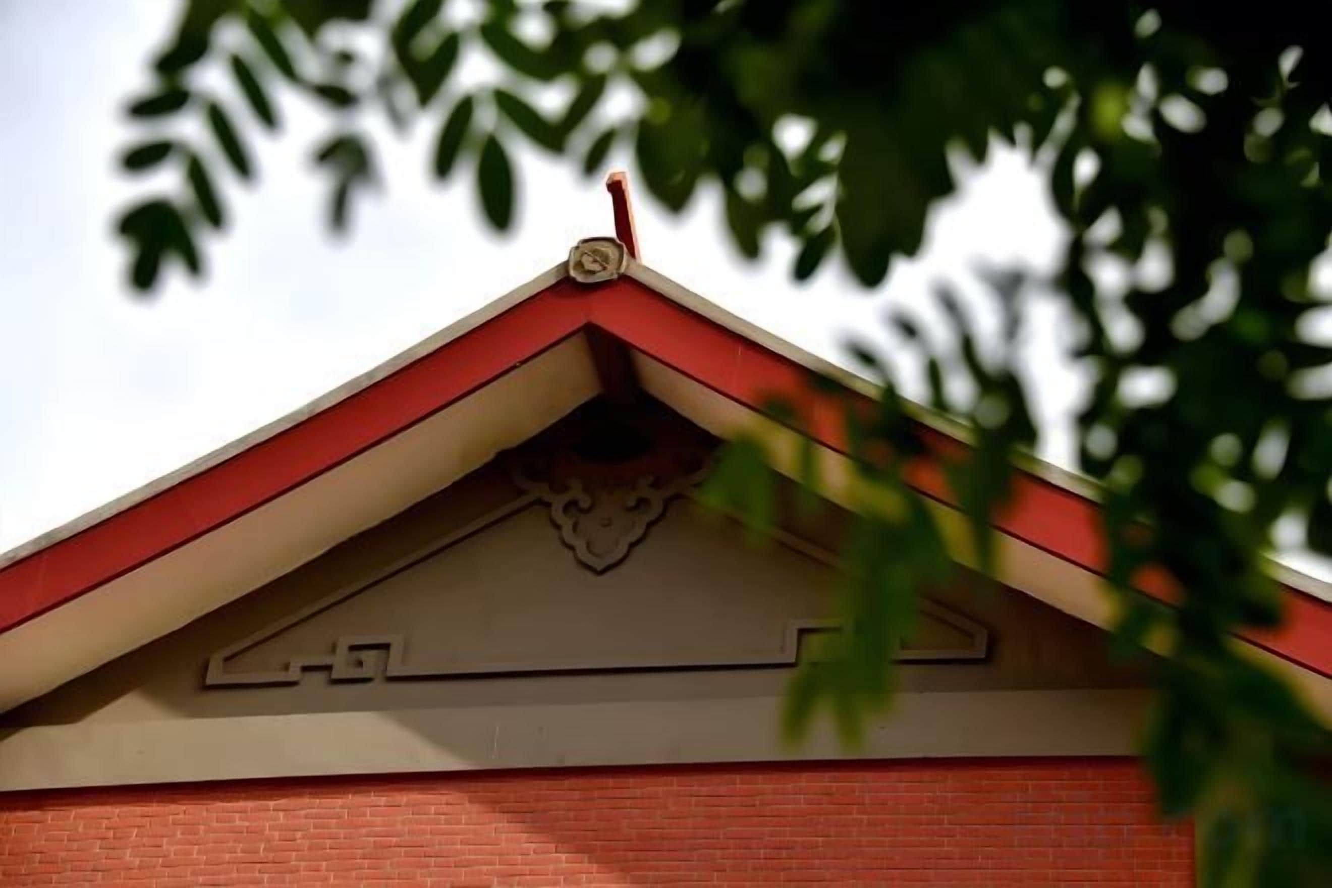 Le toit d’un bâtiment présente une combinaison de couleurs rouge et blanc, un élément décoratif et une cheminée.