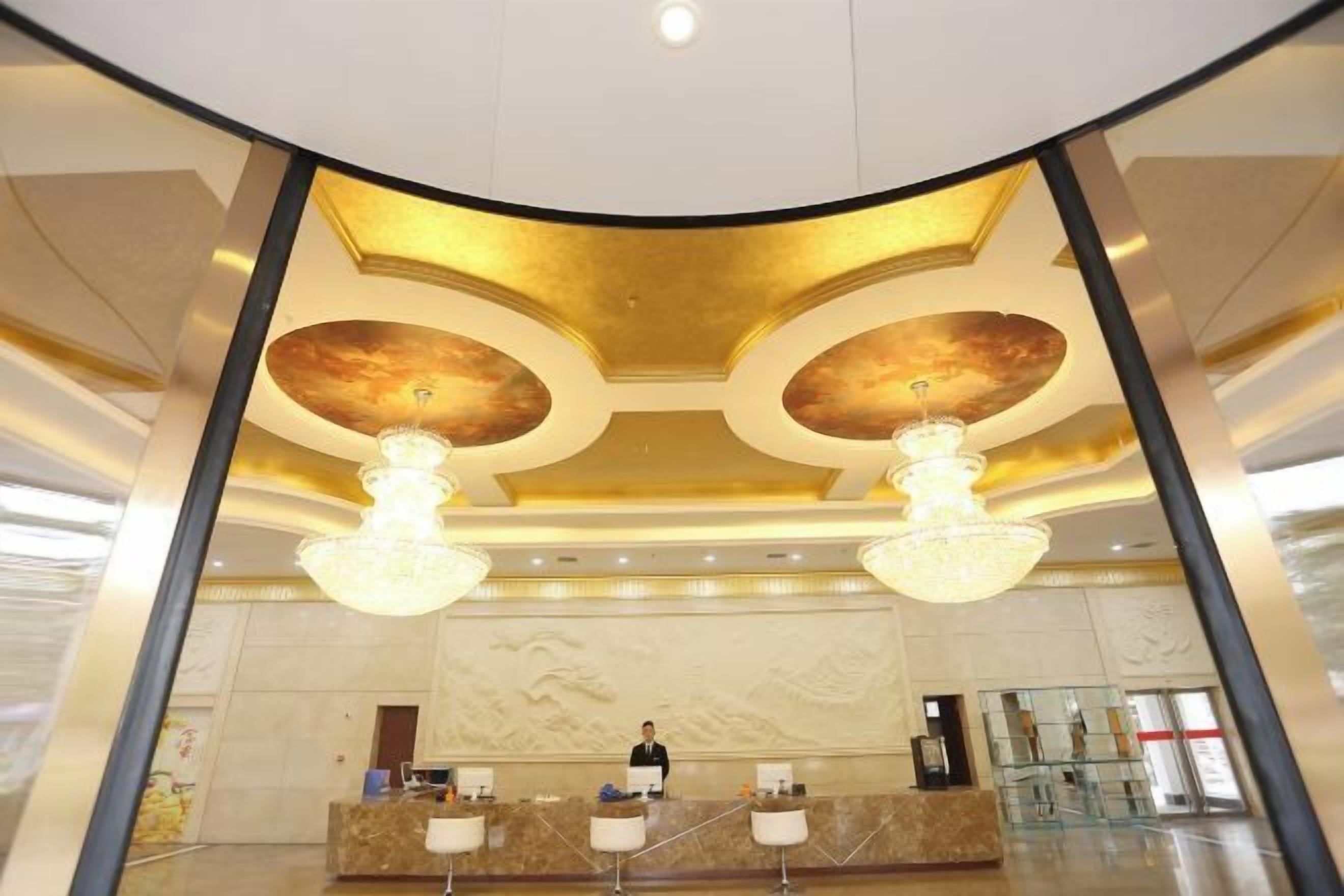 A hotel reception area with a curved ceiling, chandeliers, and a receptionist.
