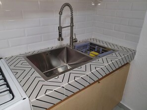 A kitchen with a stainless steel sink, a modern faucet, and a patterned countertop.