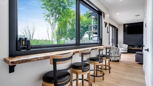 Et moderne interiør med et stort vindue, træbarstole og en siddeplads med sofa og lænestole.