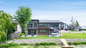 Et moderne hus i to etager med en patio, en støttemur og havudsigt.