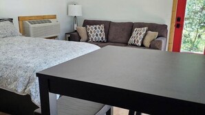 A bedroom with a bed, a sofa, a table, and a chair.