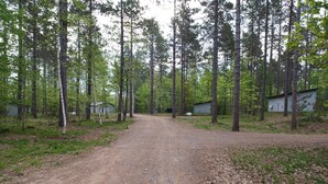 A dirt road leading through a forested area with several small buildings. - Expedition Inn (Calumet)