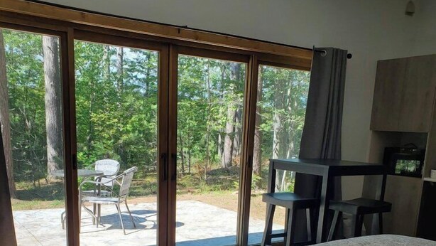 A bedroom with a large bed, a desk, and a chair. There is a sliding glass door leading to an outdoor area with a table and chairs. - Expedition Inn (Calumet)