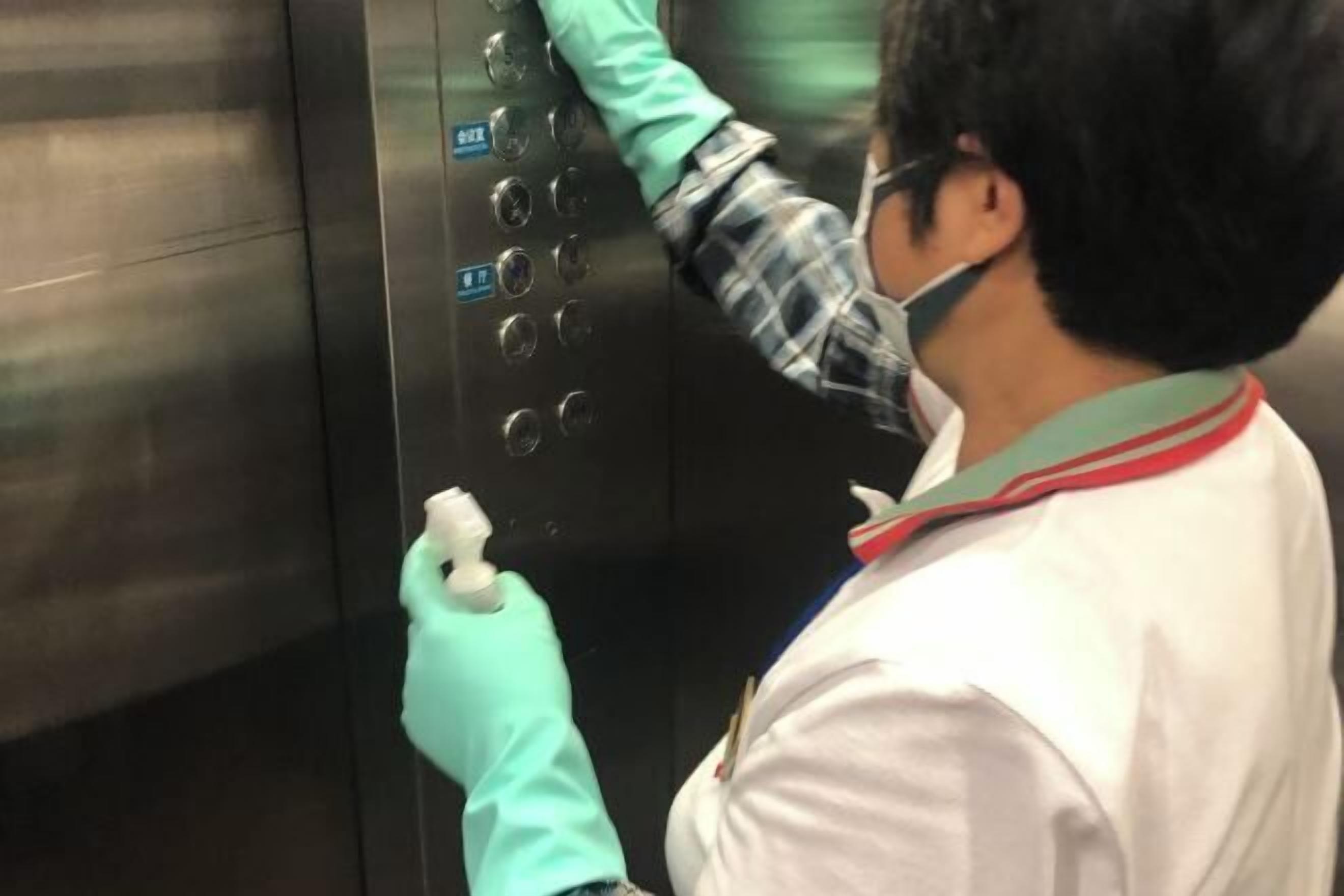 Una persona limpiando el panel de control de un ascensor.