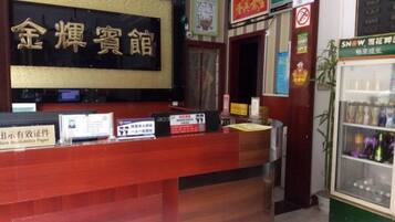 A reception desk with a sign in a foreign language, a refrigerator with beverages, and a door with a sign.