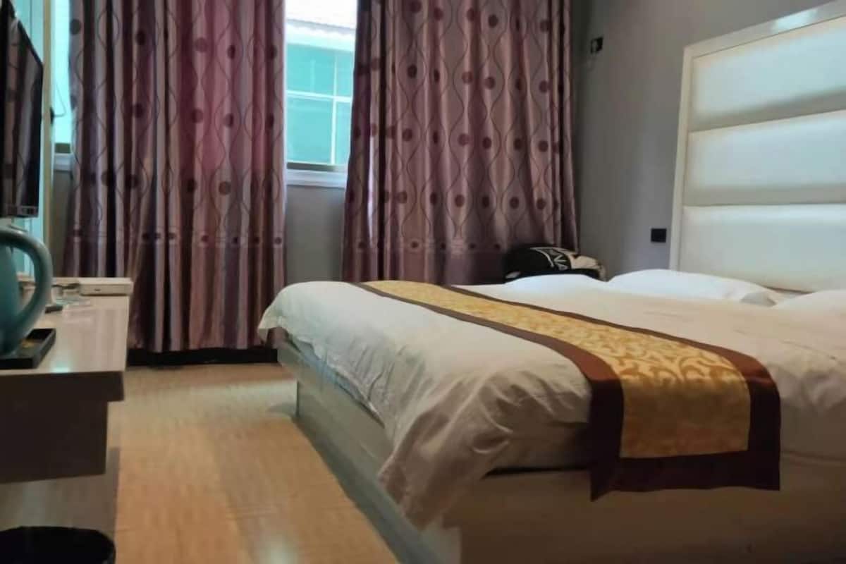 Ein Hotelzimmer mit Bett, Schreibtisch und Vorhängen.