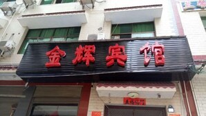 Un bâtiment sur lequel on peut voir une grande enseigne rouge avec l’inscription « 金辉宾馆 » (Jin Hui Inn).