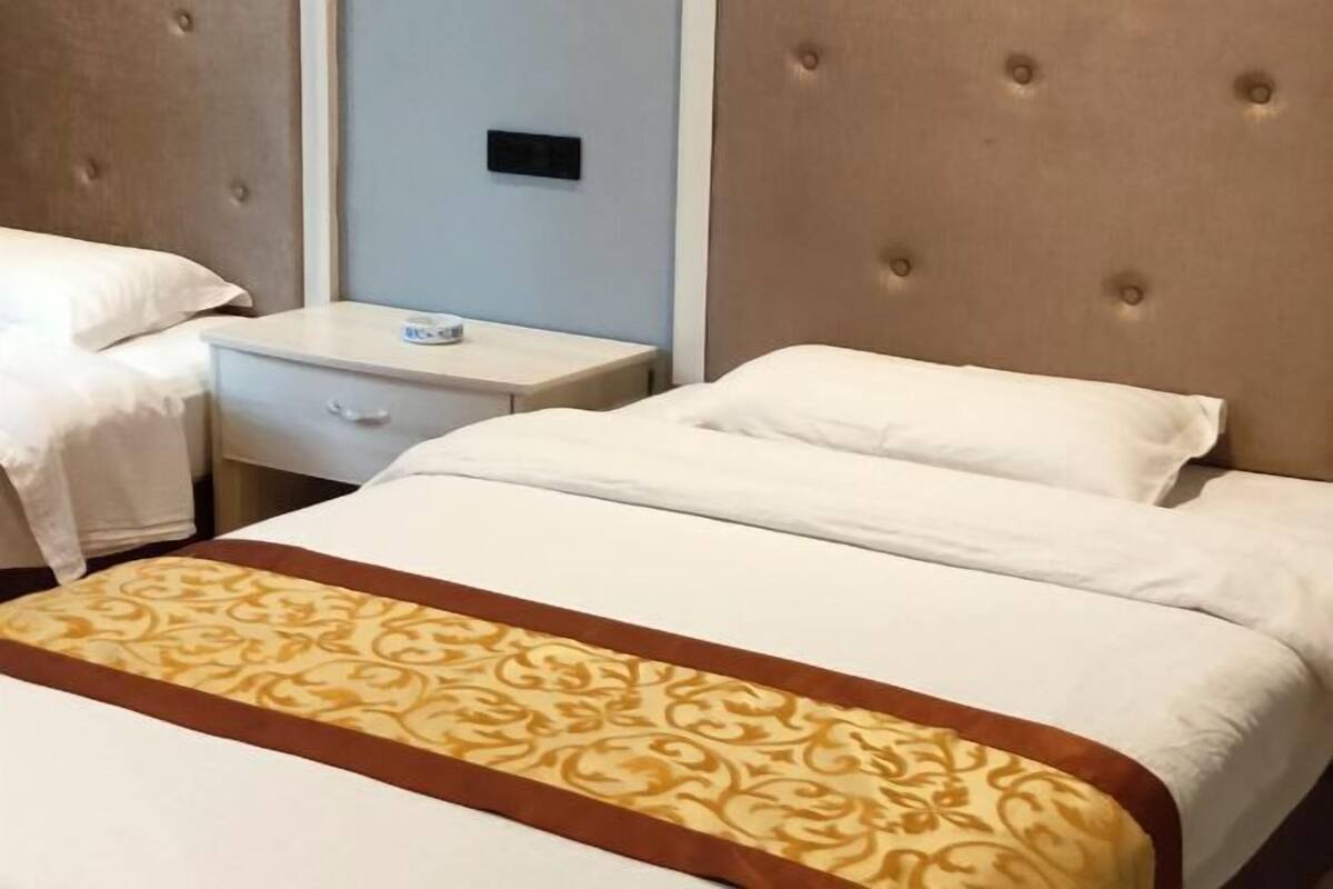 Ein Hotelzimmer mit einem großen Bett, einem Nachttisch und einer wandmontierten Bedieneinheit.