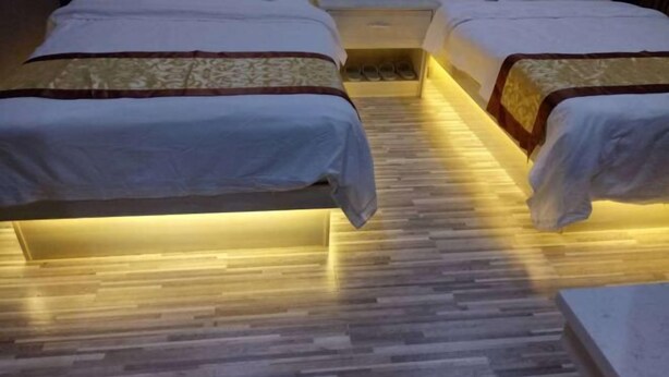 Une chambre d’hôtel avec deux lits, un plancher en bois et une table de chevet avec des chaussons.