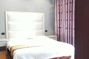 Ein Hotelzimmer mit einem großen Bett, einem Nachttisch und einem Holzkopfstück.