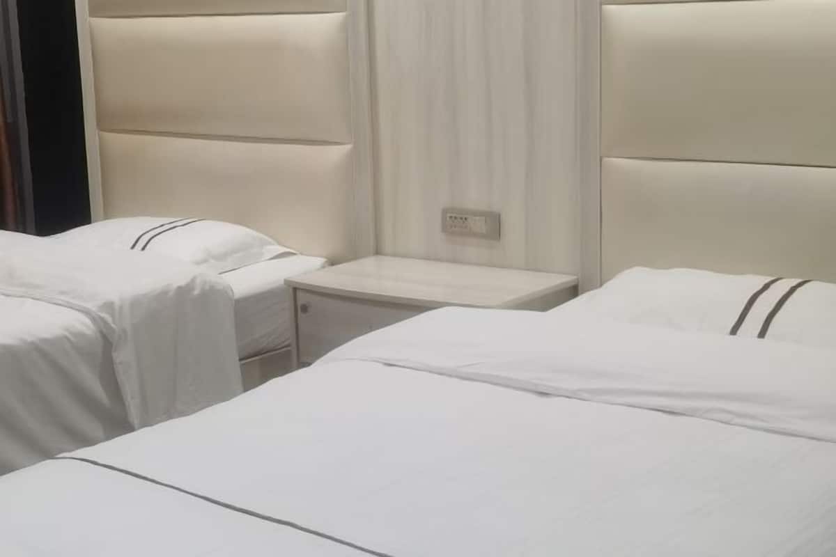 Ein Hotelzimmer mit zwei Betten, jeweils mit Kopfteil und Nachttisch.