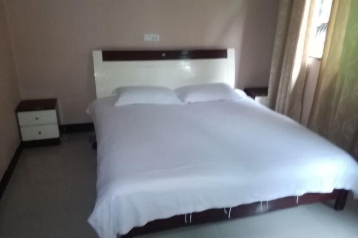 Ein Hotelzimmer mit Bett, Nachttisch und einer fest montierten Bedienkonsole.