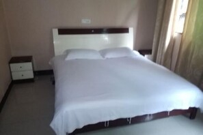 Ein Hotelzimmer mit Bett, Nachttisch und einer fest montierten Bedienkonsole.