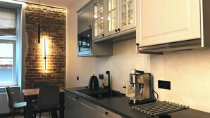 A modern kitchen with a brick wall, white cabinets, and a built-in oven. - Charm & Comfort Renovated Gem in Old Town 8 min walk to Krakow’s Main Square!  (Kraków)