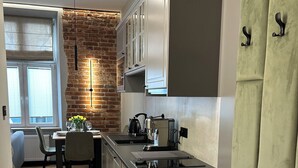 A modern kitchen with a herringbone wood floor, a brick accent wall, and a dining area with a table set for four. - Charm & Comfort Renovated Gem in Old Town 8 min walk to Krakow’s Main Square!  (Kraków)