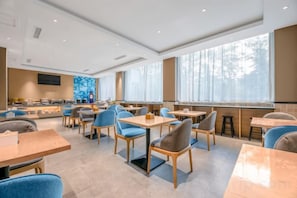 A modern restaurant with a variety of seating options including tables and booths, large windows providing natural light, and a clean, contemporary interior design.
