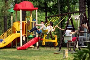 Un parque infantil con columpios y un tobogán.