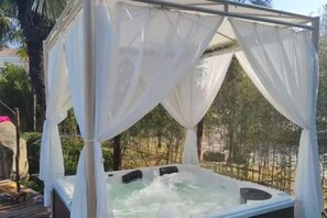 Un bain à remous doté d’un auvent, entouré de verdure.