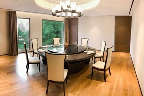 Een moderne eetruimte met een ronde tafel, zes stoelen en een kroonluchter.