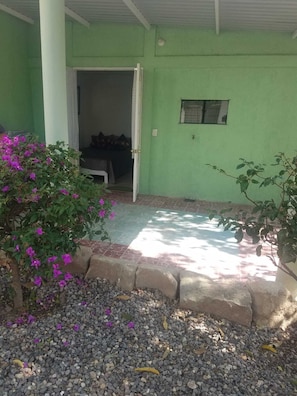 A green exterior with a covered porch, a small window, and a doorway leading to an interior space. - Studio cottage ideally located in Oaxaca's Historical District (Oaxaca de Juárez)