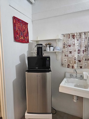 Compact kitchenette with a refrigerator, microwave, sink, and ample storage for kitchen essentials.