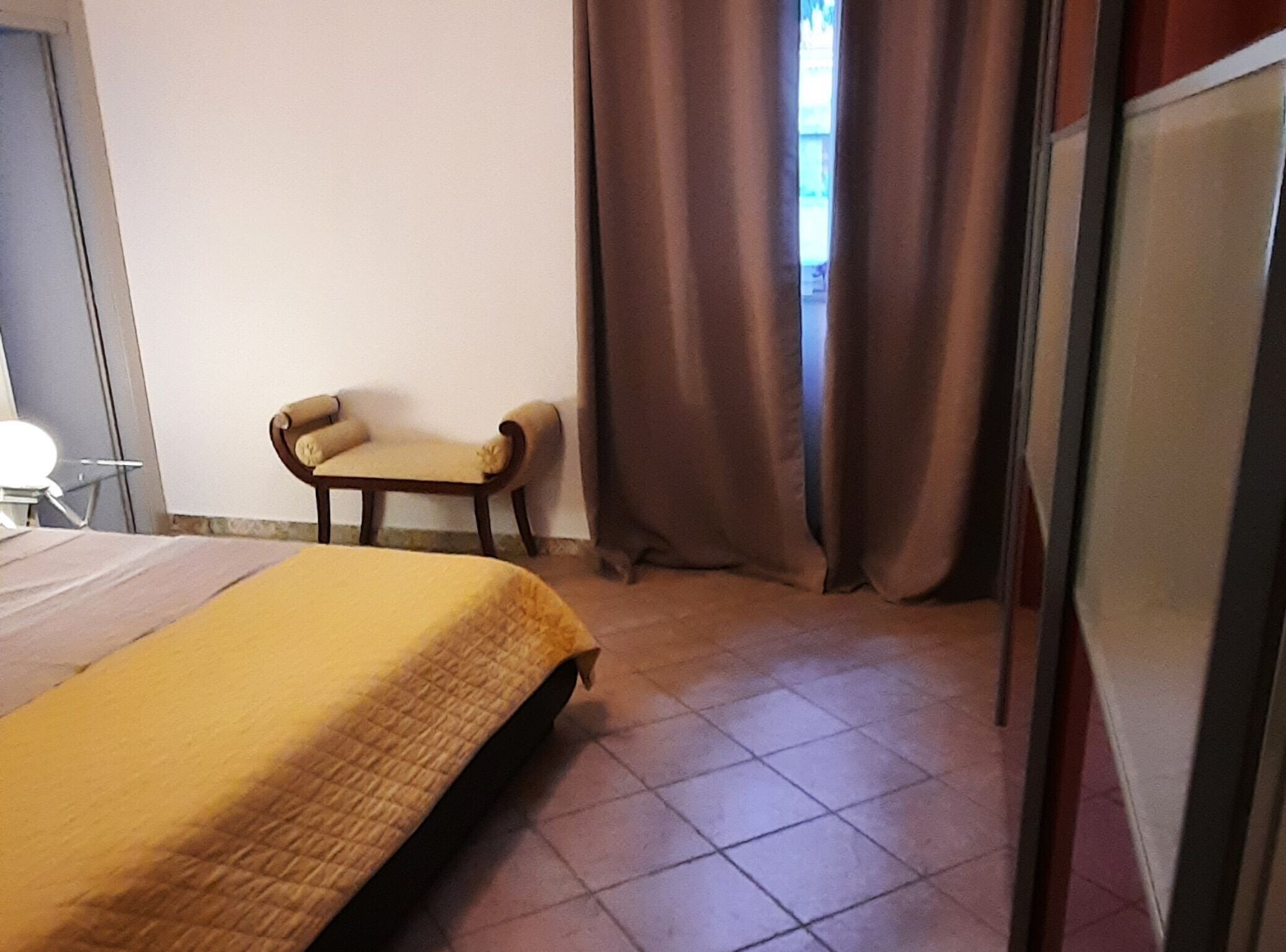 A room with a bed, a chair, and a window with curtains.