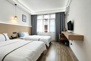 Habitación de hotel con dos camas, un escritorio, un televisor y una ventana con cortinas.