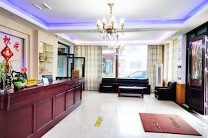 Um saguão de hotel com balcão de recepção, área de estar e um lustre.