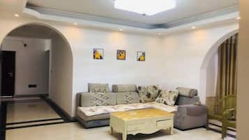 A living room with a sofa, a coffee table, and a chair. There are three framed pictures on the wall.