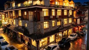 A multi-story building with traditional architecture, multiple balconies, and a row of parked cars. - Hongya Hansongyuan Inn (Hongya)